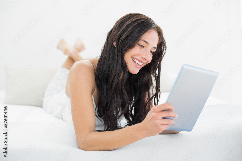 Smiling woman using tablet PC in bed Smiling woman using tablet PC in bed