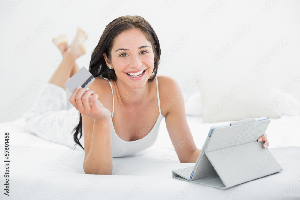 Casual young woman doing online shopping in bed Casual young woman doing online shopping in bed