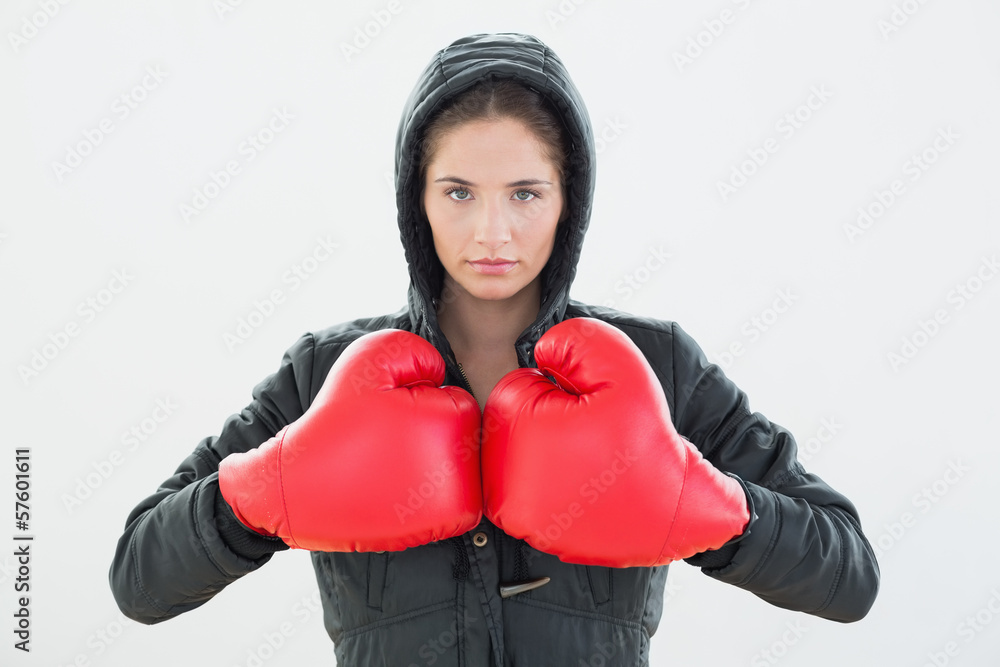 Serious young woman in red boxing gloves and black hood Serious young woman in red boxing gloves and black hood