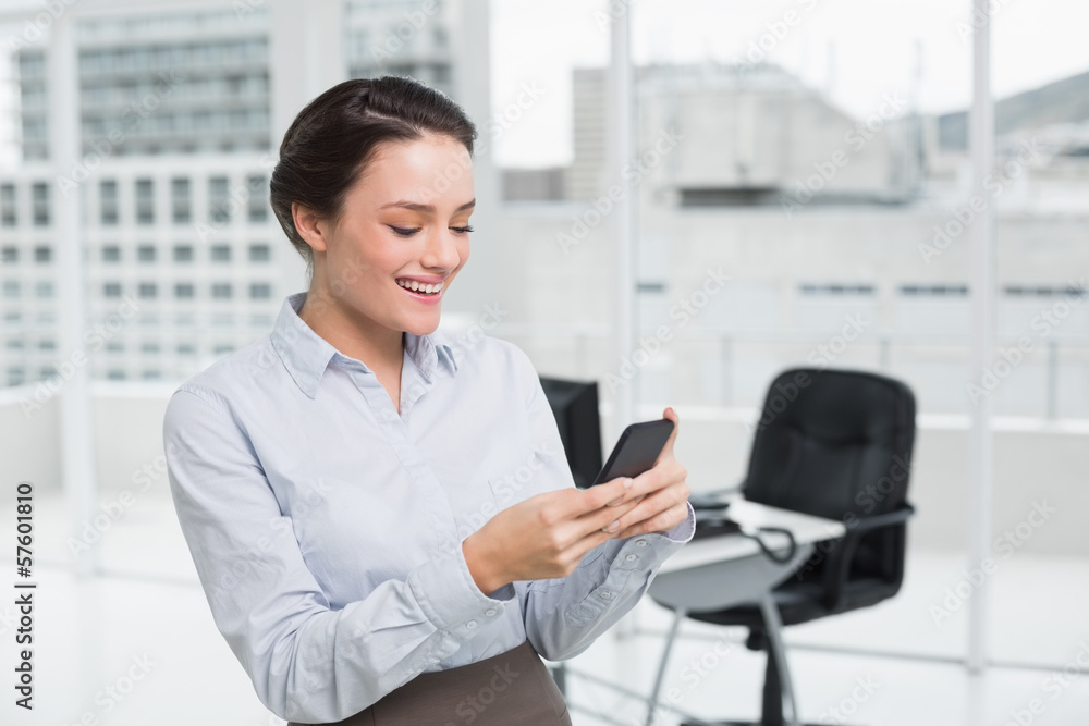 Smiling businesswoman reading text message in office