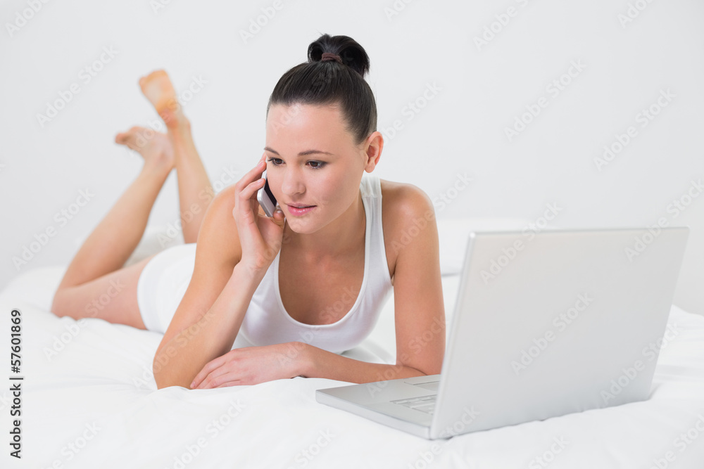 Casual woman using cellphone and laptop in bed Casual woman using cellphone and laptop in bed