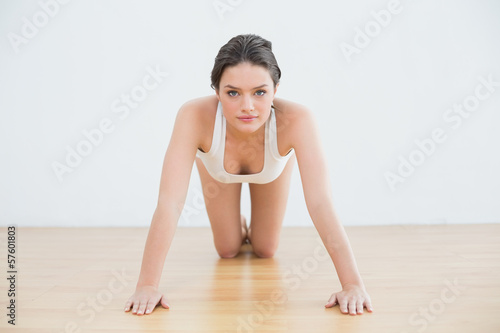 Sporty young woman doing push ups in fitness studio