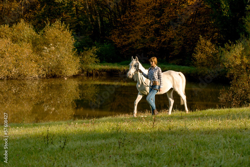 Young woman with horse in the lake