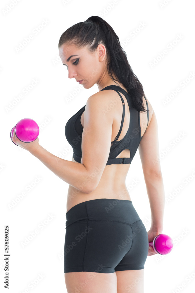 Beautiful fit woman training her arms with pink dumbbells Beautiful fit woman training her arms with pink dumbbells