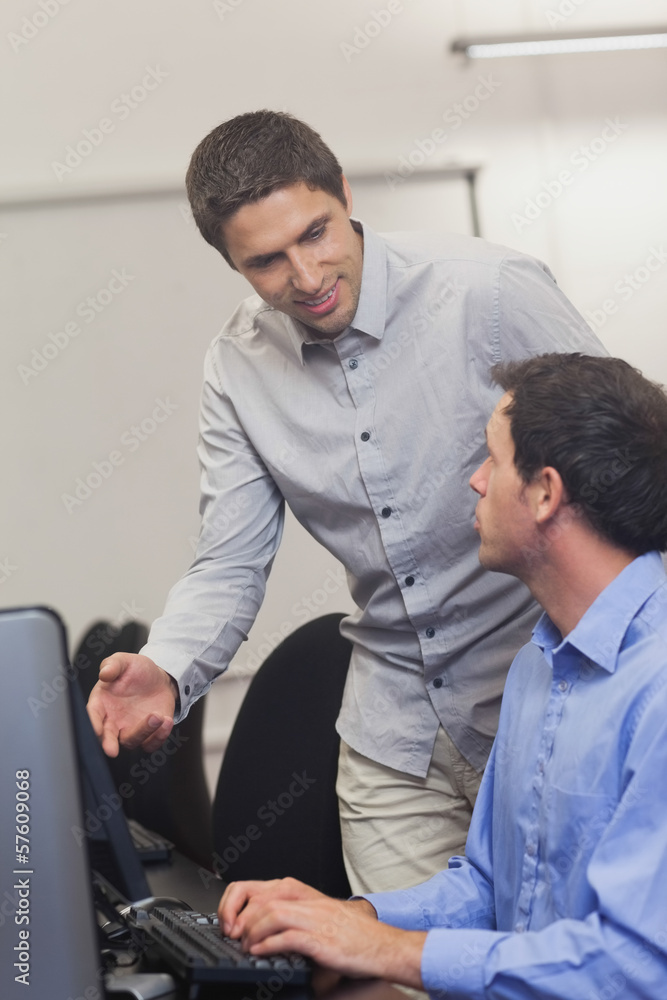 Attractive teacher talking to his student in computer class Attractive teacher talking to his student in computer class