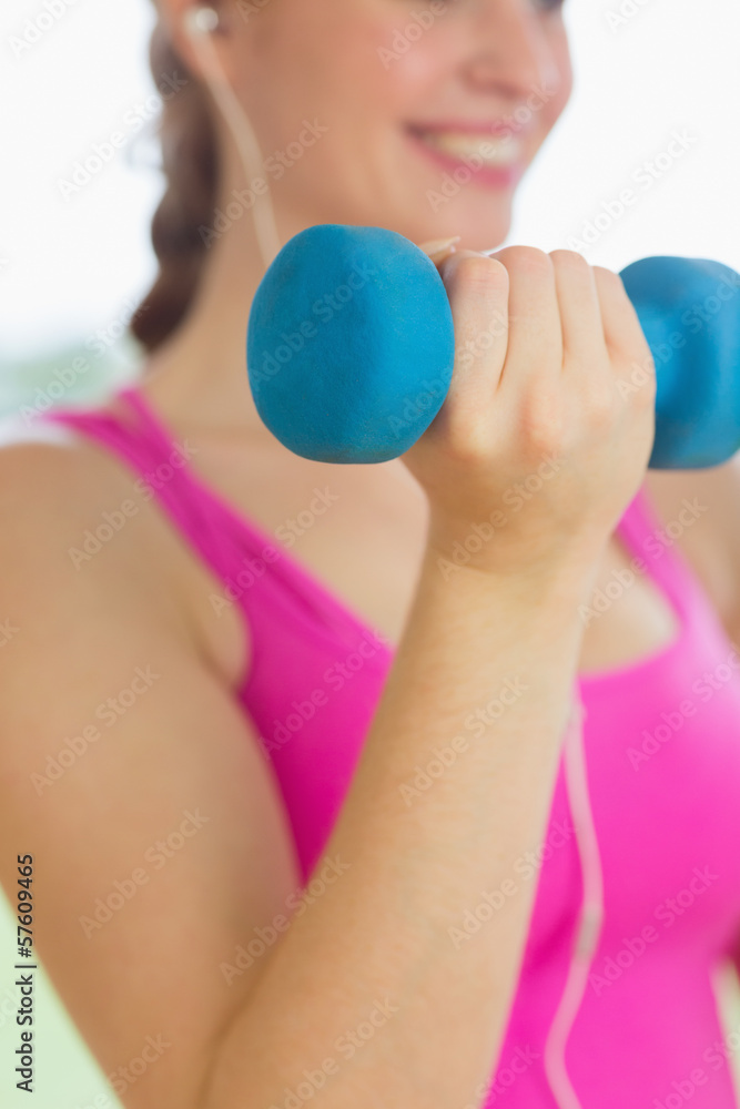 Mid section of a woman exercising with dumbbells Mid section of a woman exercising with dumbbells