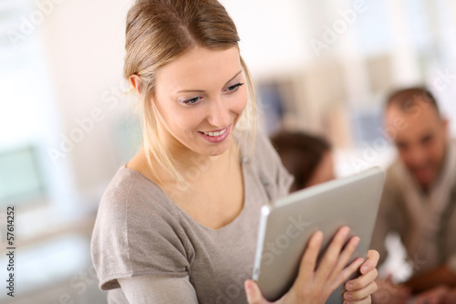 Beautiful young woman at work using tablet