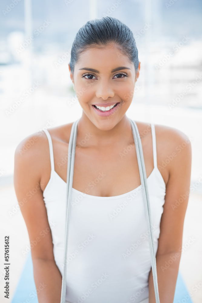 Gleeful toned brunette sitting on floor with skipping rope Gleeful toned brunette sitting on floor with skipping rope