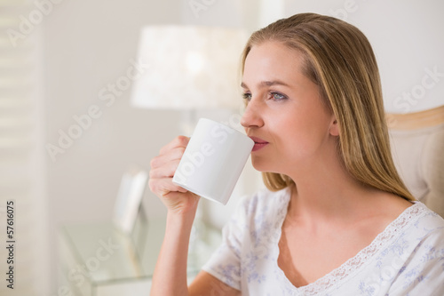 Natural content woman sitting on bed drinking
