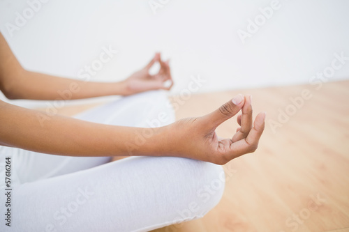 Mid section of slim young woman meditating sitting in lotus posi
