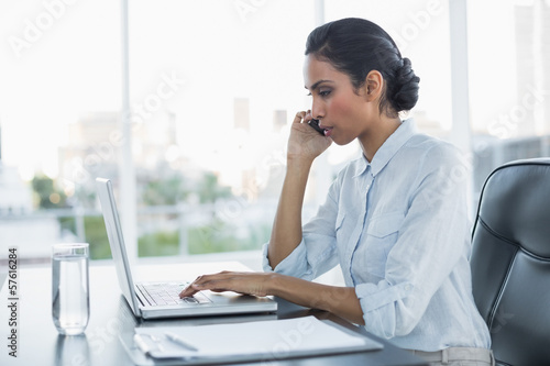 Calm concentrated businesswoman sitting at her desk working