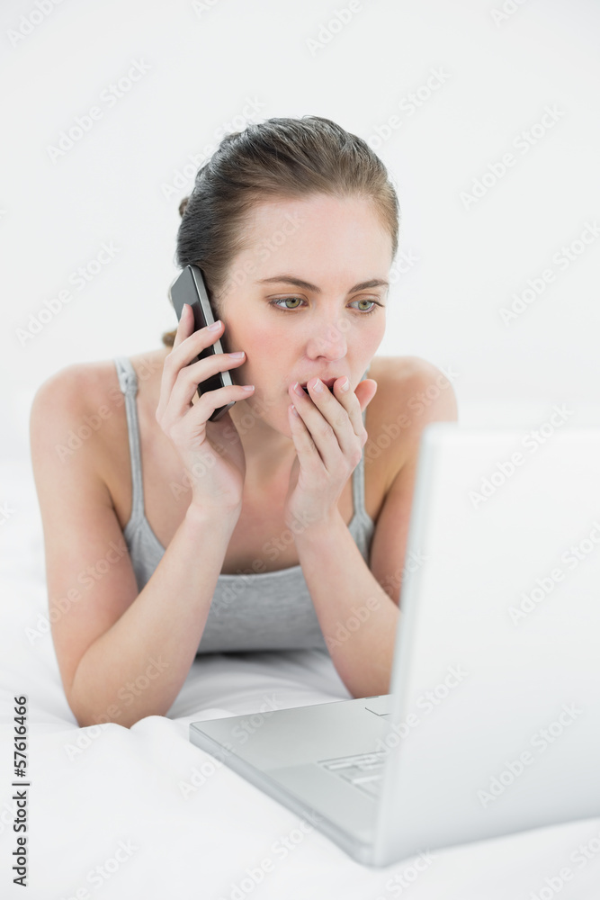 Shocked casual woman using cellphone and laptop Shocked casual woman using cellphone and laptop