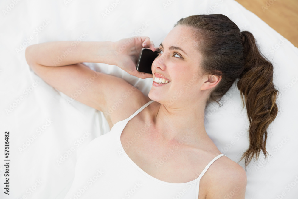 Smiling woman using mobile phone in bed Smiling woman using mobile phone in bed