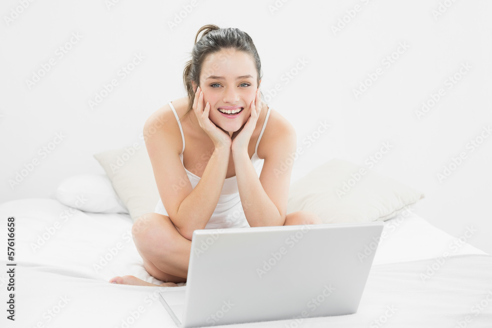 Smiling casual woman with laptop sitting on bed Smiling casual woman with laptop sitting on bed