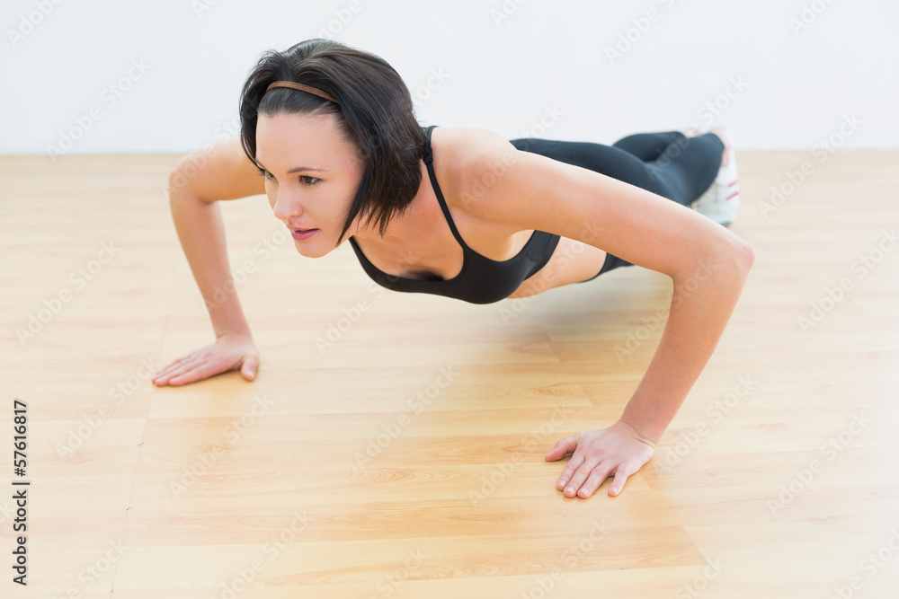 Determined woman doing push ups in fitness studio Determined woman doing push ups in fitness studio