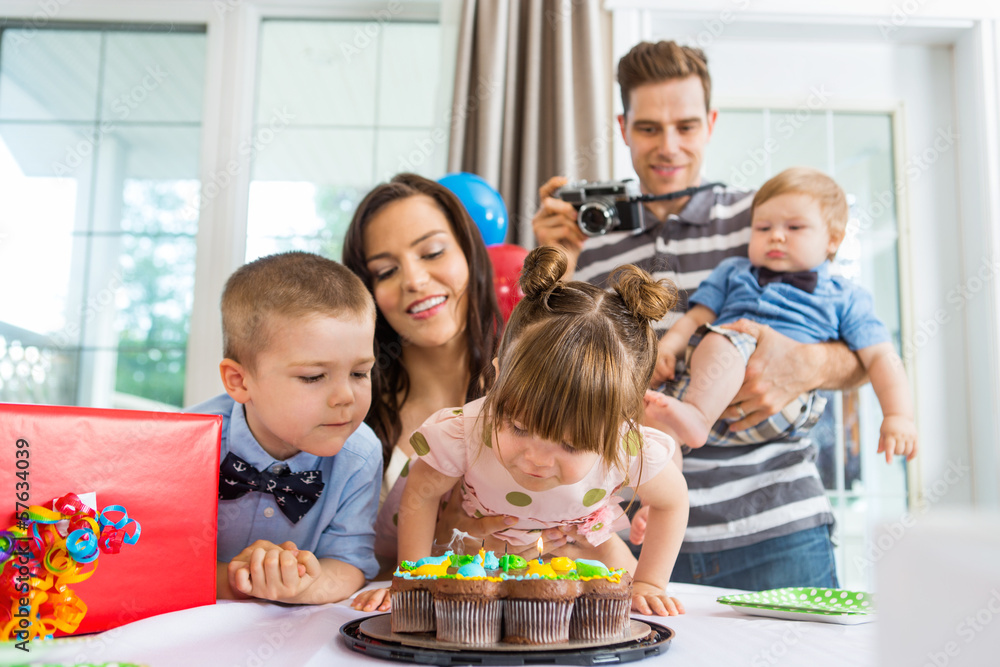 Family Watching Girl Blowing Out Candles On Birthday Cake Family Watching Girl Blowing Out Candles On Birthday Cake