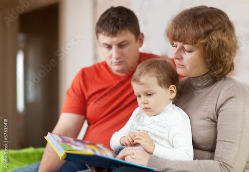  parents with child looks the book