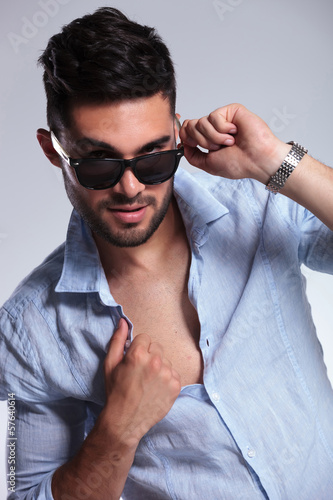 casual man pulls down sunglasses and opens shirt