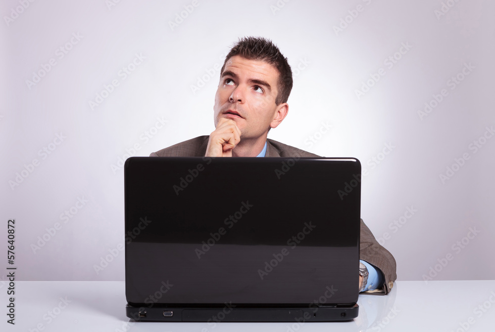 pensive young business man behind laptop looks away pensive young business man behind laptop looks away