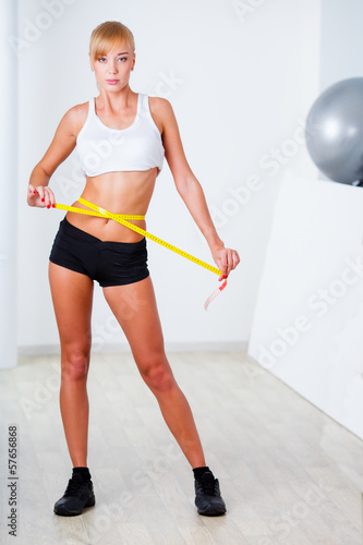 blonde woman measuring her waistline