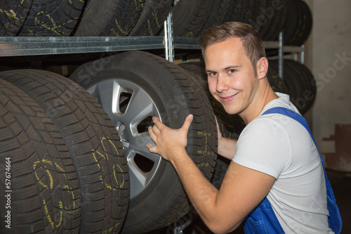 Mechanic in wheel or tire storehouse of a garage photo