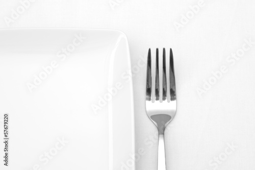 White plate with fork on white table cloth