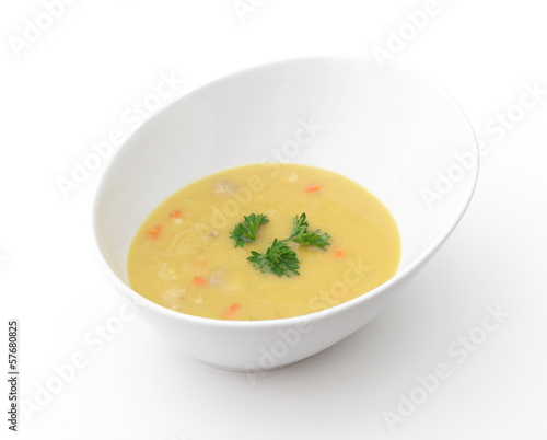 A bowl of yellow split-pea soup on a white background