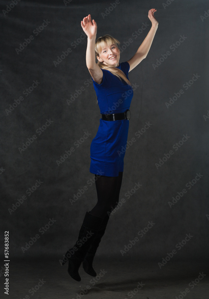Success - young active businesswomen jumping in blue dress.