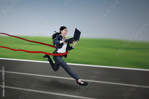 Executive businesswoman running and holding laptop