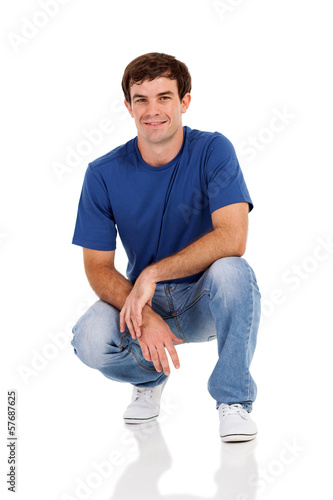 casual man squatting on white