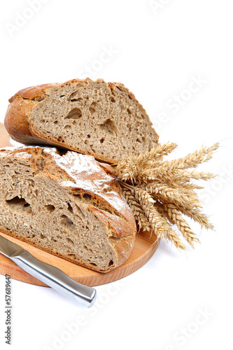 Two halves a loaf of rye bread with a knife and wheat ears.