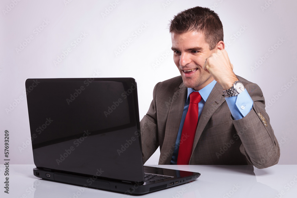 young business man cheers while reading on laptop young business man cheers while reading on laptop