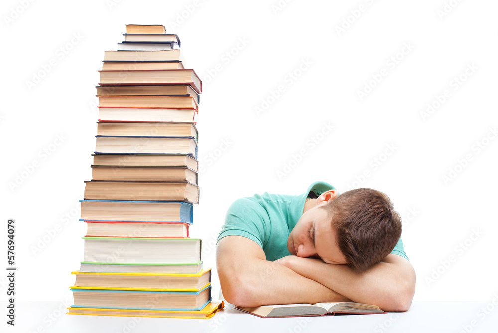 Sleeping student sitting at the desk with high books stack Sleeping student sitting at the desk with high books stack