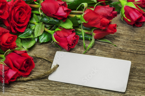 Red roses bouquet with blank sheet on wood
