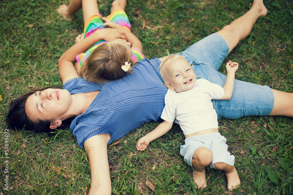 Joyful family enjoying themselves laying on grass Joyful family enjoying themselves laying on grass