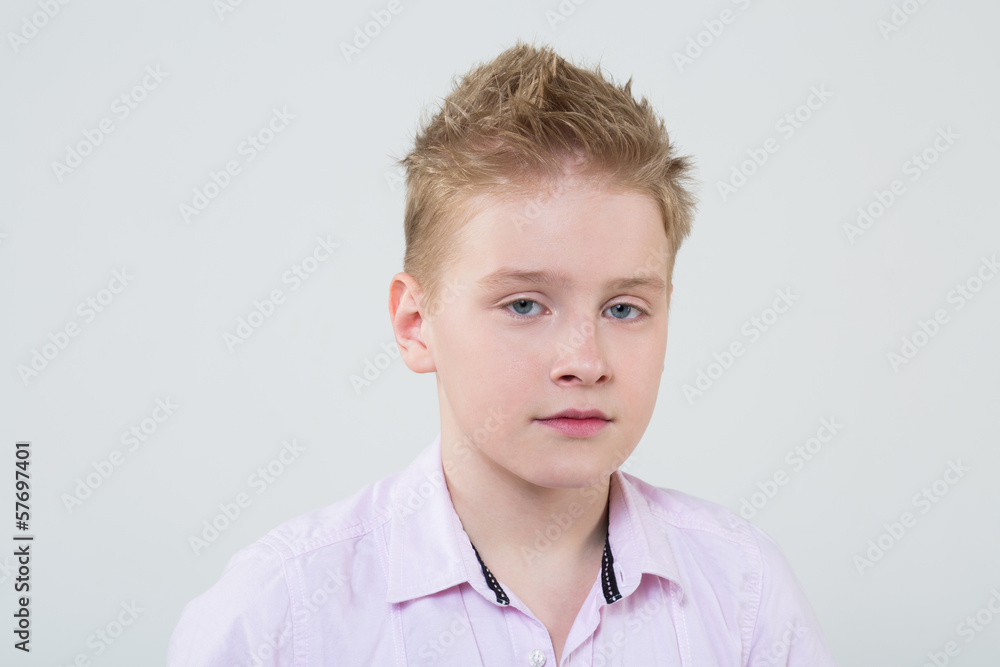 Calm boy in a pink shirt with ruffled hair in the studio Calm boy in a pink shirt with ruffled hair in the studio