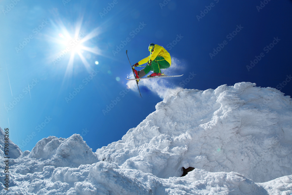 Skier jumping against blue sky in high mountain