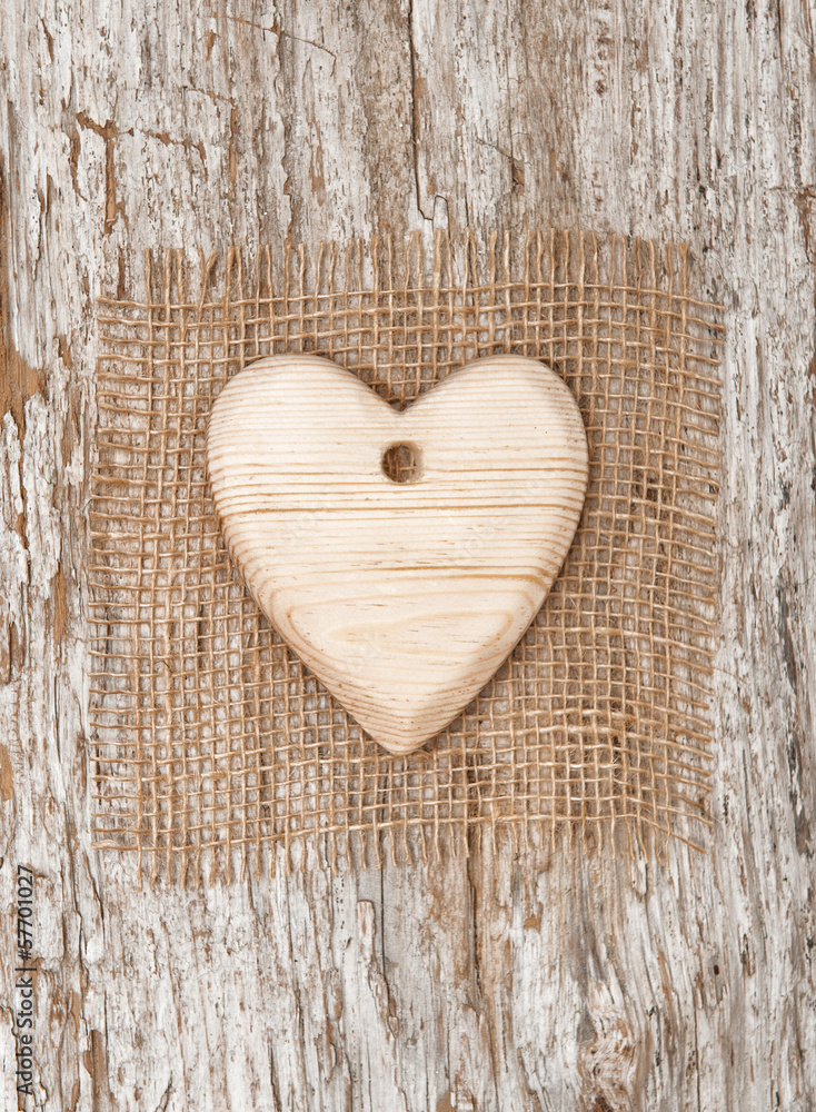 Wooden heart with burlap textile on the old wood Wooden heart with burlap textile on the old wood
