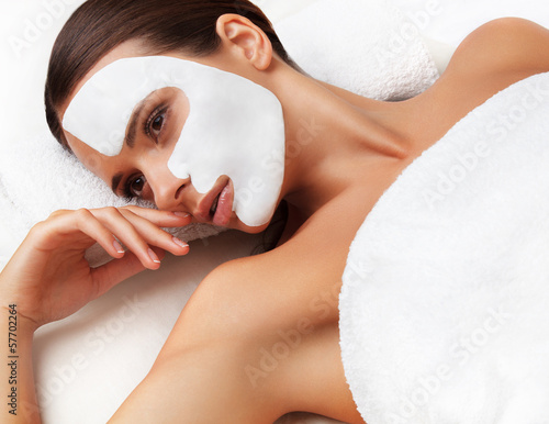 Young woman at spa salon with cosmetic mask on face.