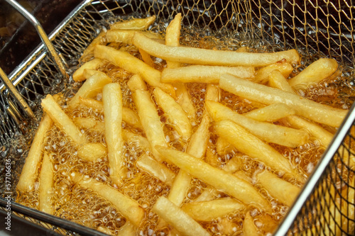 Fototapeta French fries in a deep fryer closeup