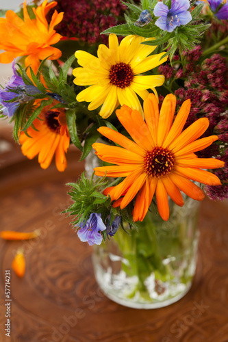 Bouquet of autumn flowers in vase on wooden background