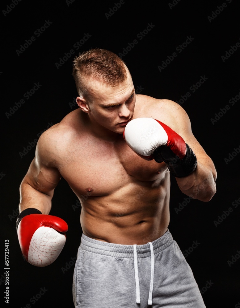 Handsome muscular young man wearing boxing gloves