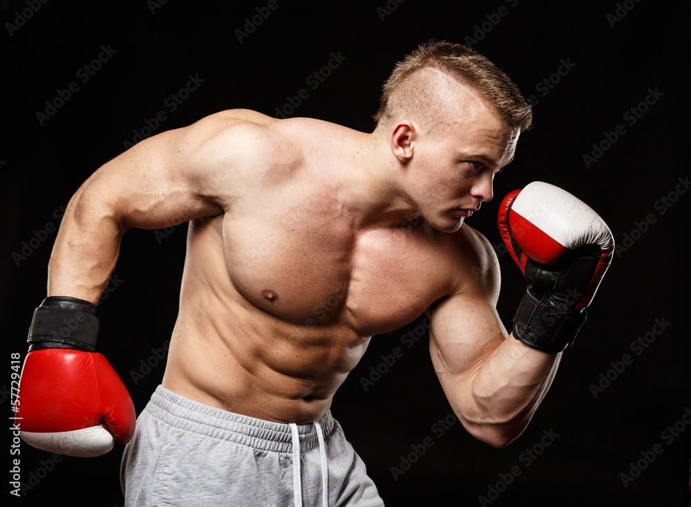Handsome muscular young man wearing boxing gloves