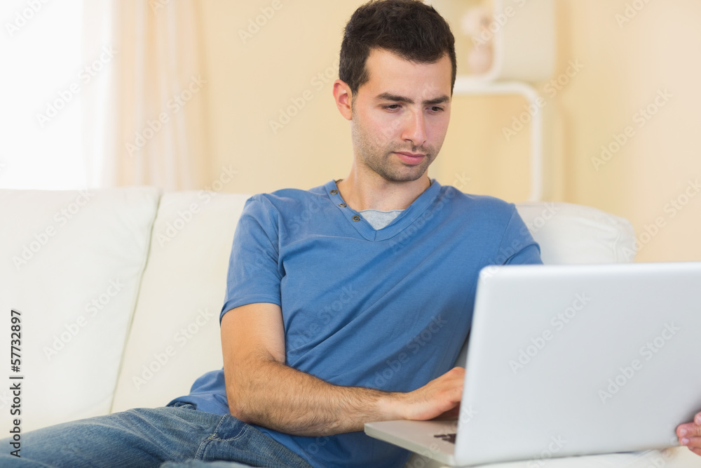 Casual peaceful man sitting on couch using laptop Casual peaceful man sitting on couch using laptop