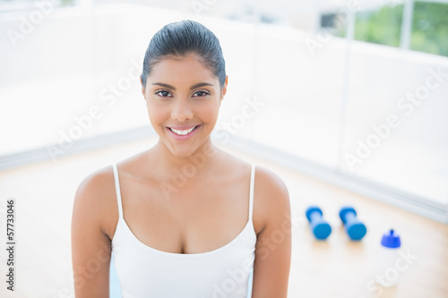 Smiling toned brunette sitting on floor