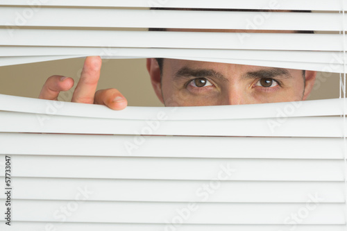 Focused male eyes spying through roller blind photo