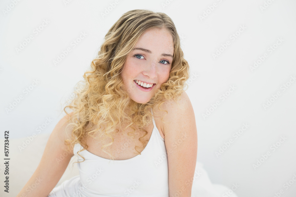 Pretty gleeful blonde sitting on bed looking at camera Pretty gleeful blonde sitting on bed looking at camera