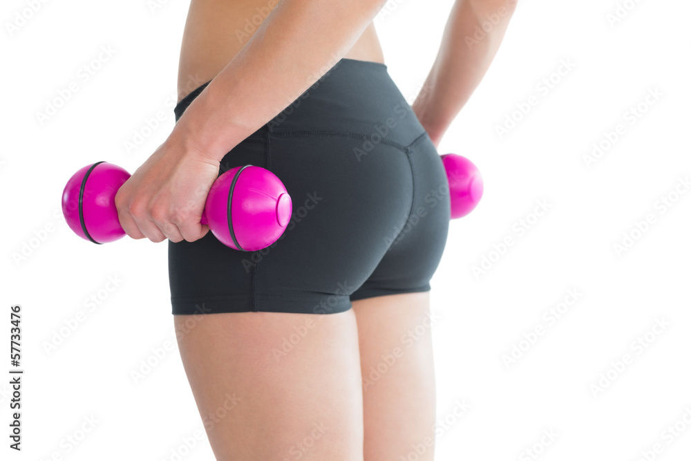 Close up of female bottom while training with pink dumbbells Close up of female bottom while training with pink dumbbells