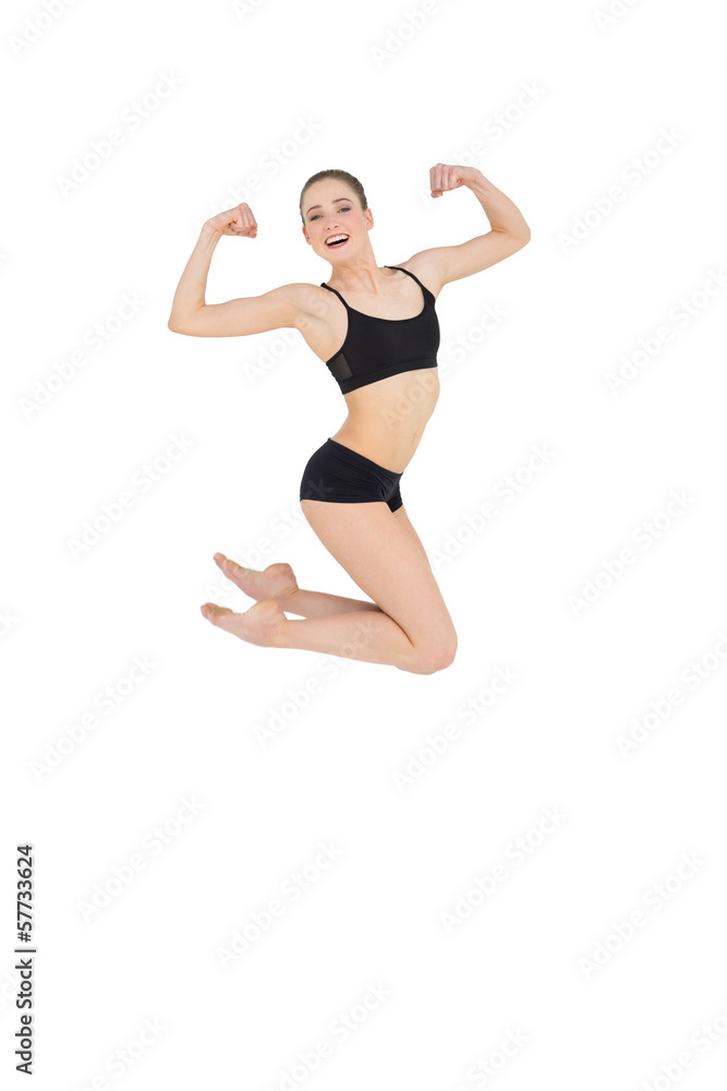 Strong slim model jumping in the air flexing her muscles