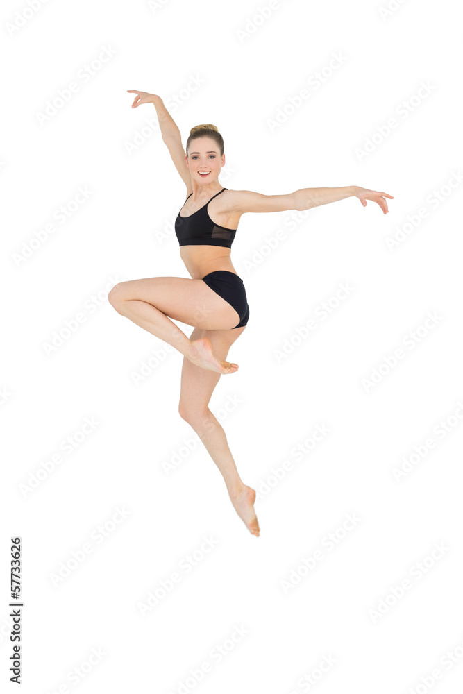 Smiling slim ballet dancer jumping in the air